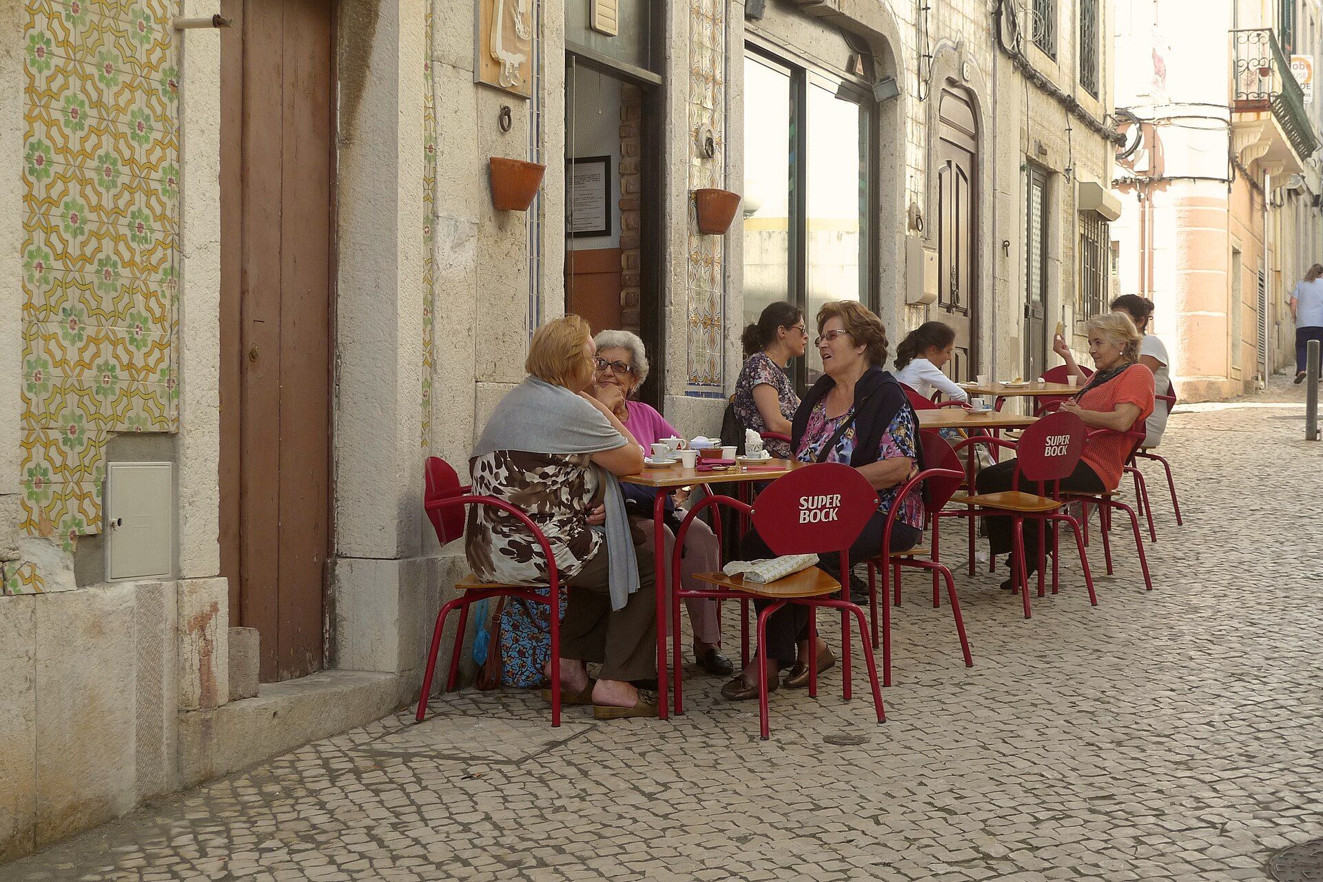 Senhoras sentadas numa esplanada de café numa rua estreita de Sesimbra