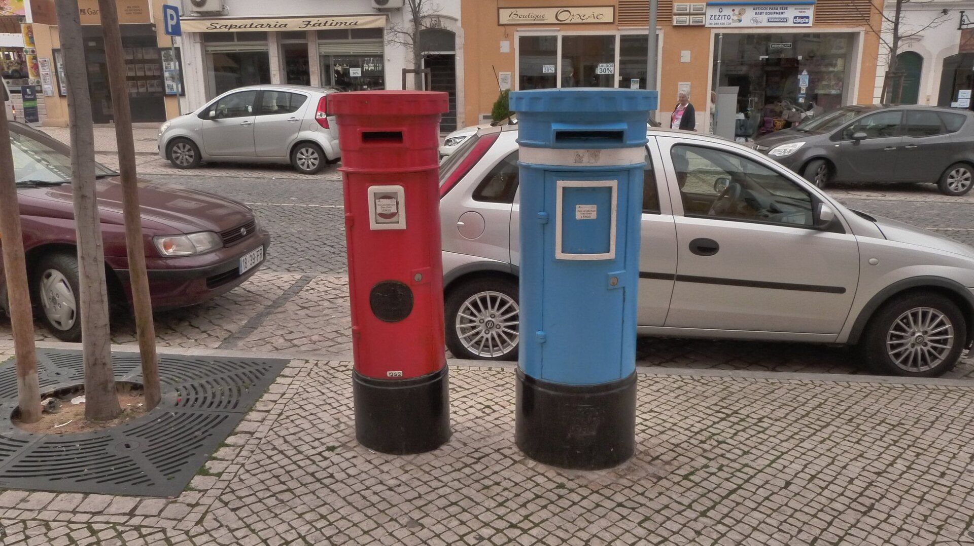 Dois marcos do correio dos CTT, um vermelho e um azul, numa rua de Portugal