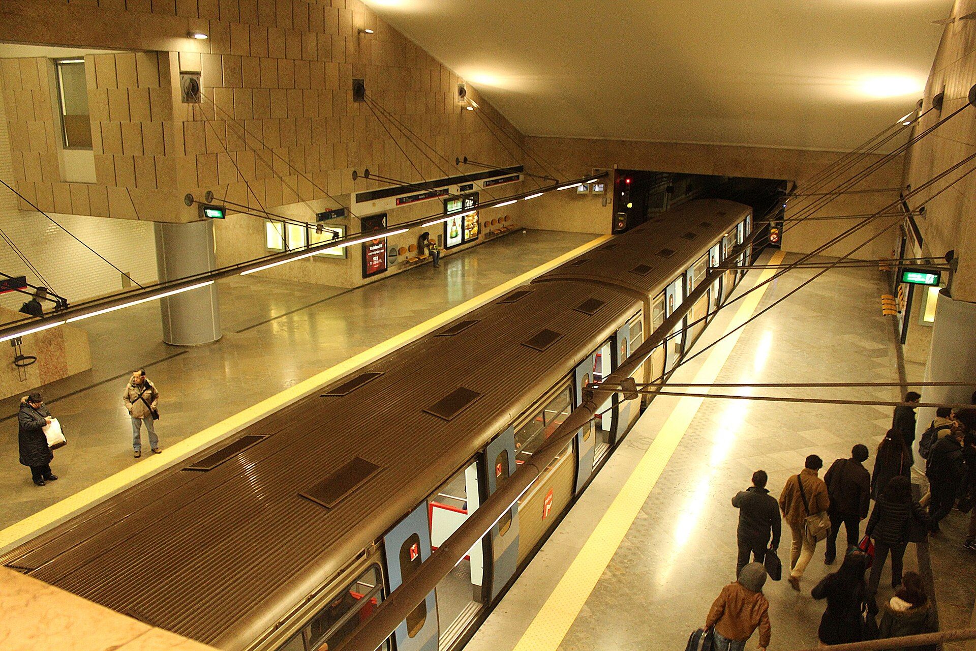 Estação de metro da Alameda, em Lisboa, com um comboio parado e passageiros no cais
