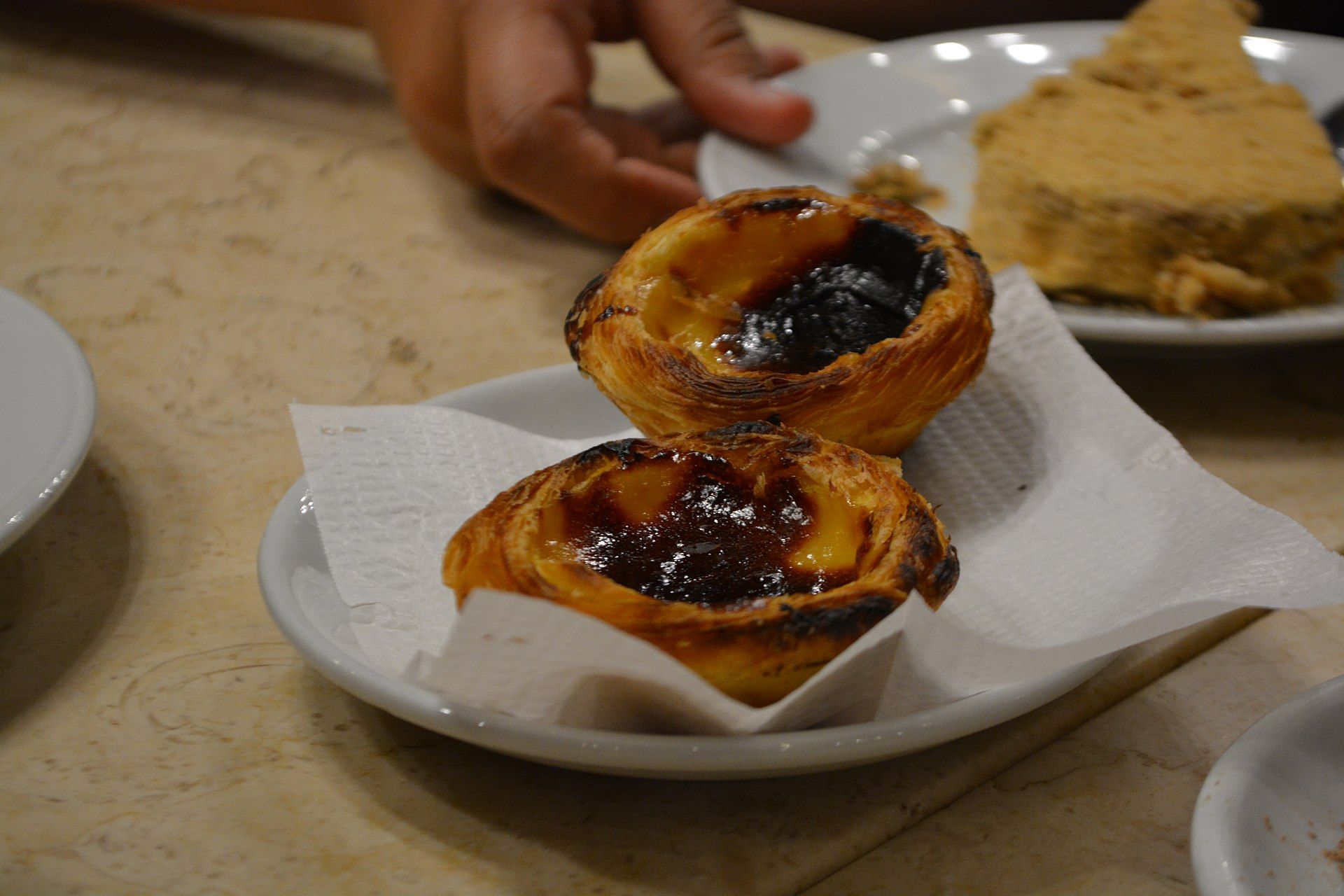 Dois pastéis de nata num prato, ao balcão de um café em Lisboa
