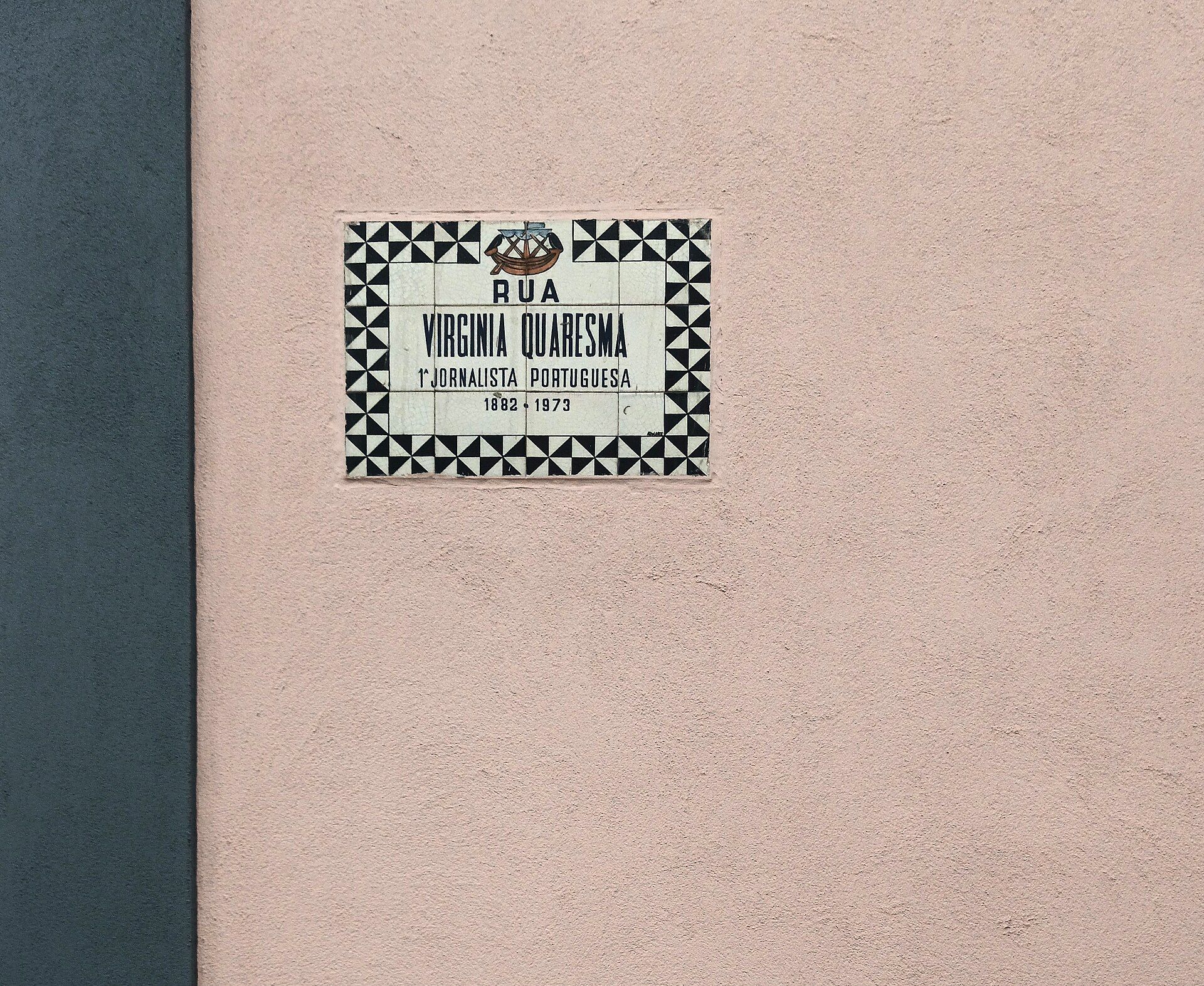 Placa de rua em azulejo branco e azul numa parede de Lisboa