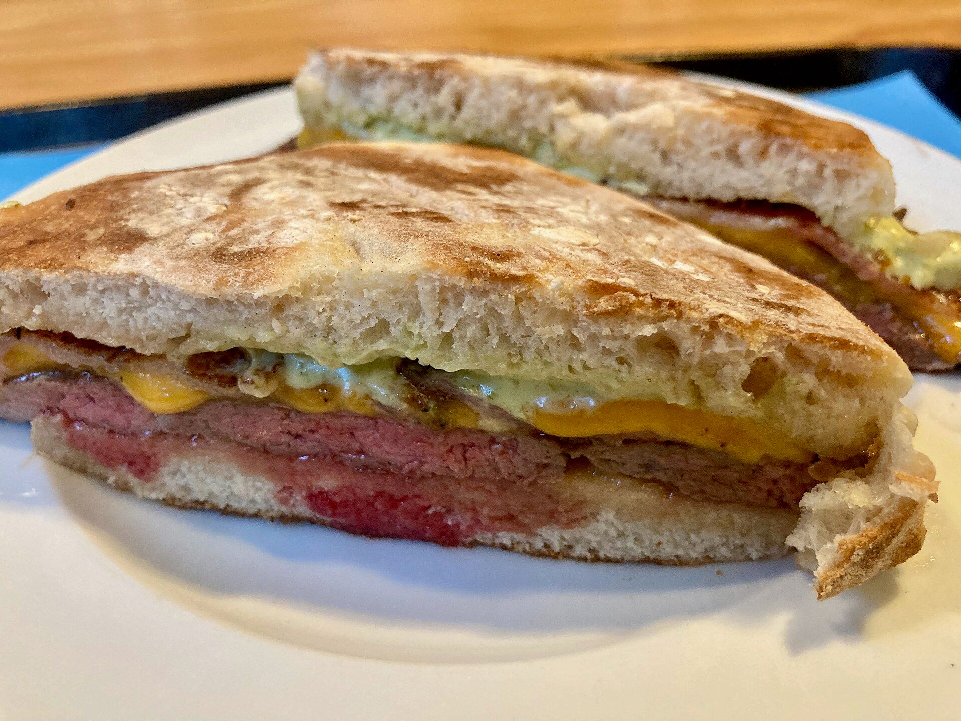 Prego no pão, uma sandes de bife com queijo, cortada ao meio num prato